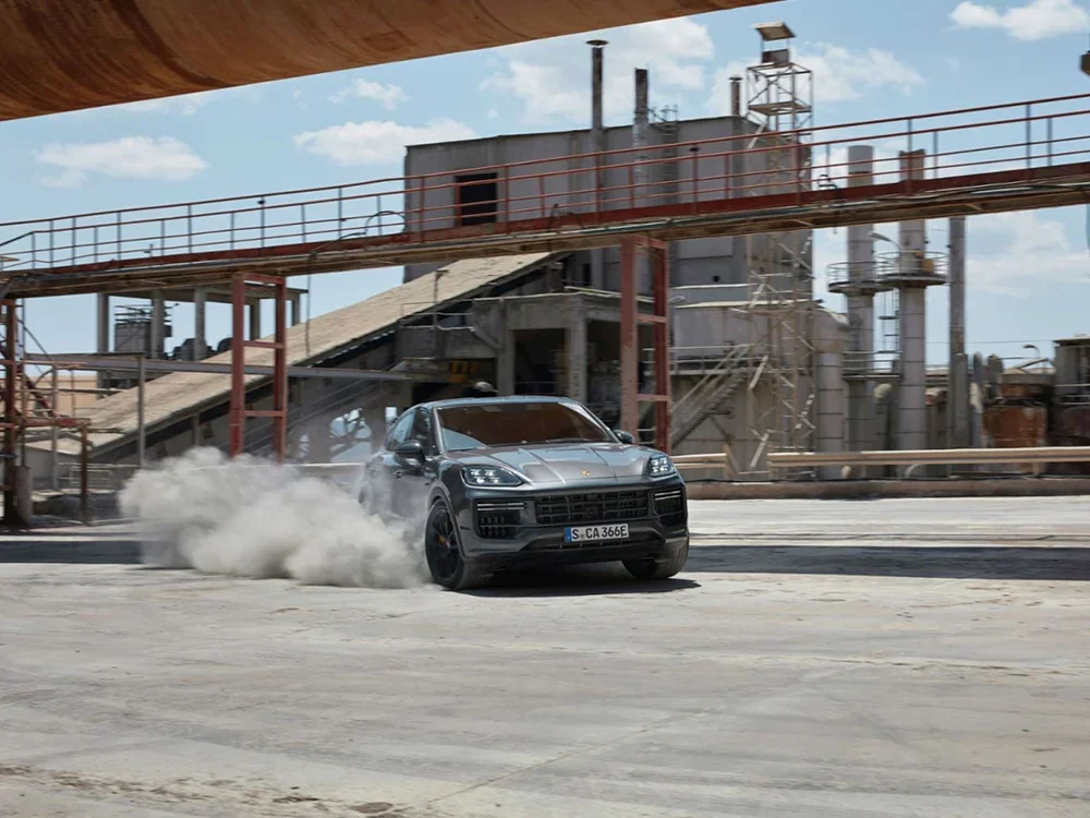 Porsche Cayenne Coupe in Quarzite Grey Metallic with black wheels and porsche yellow calipers doing driving techniques in Fort Collins, Colorado