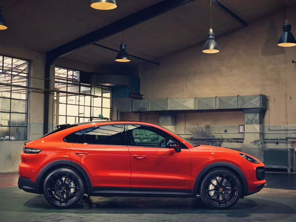 Orange Porsche Cayenne Coupe with black wheels parked in a warehouse in Boulder, Colorado